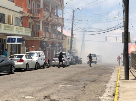 Téléchargez les photos : Fumée remplit une rue dans st Kitts île que les gens marchent - en image libre de droit