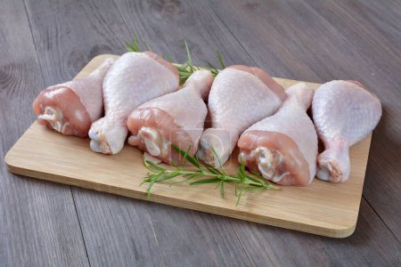 raw chicken legs on a wooden board
