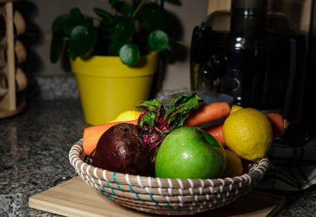 Foto de Frutas y verduras: zanahoria, remolacha, manzana verde, limón, en un tazón natural de paja listo para cocinar o hacer jugo fresco exprimir con exprimidor en el fondo - Imagen libre de derechos