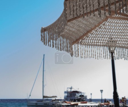 Photo for Macrome summer sun umbrella in beach club or cafe, boats and sea on background - Royalty Free Image
