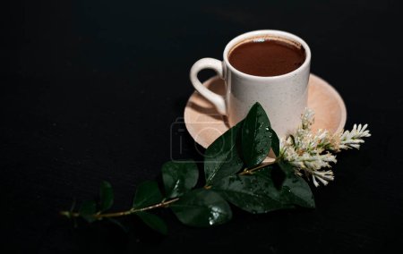 Foto de Café tradicional turco sobre fondo oscuro, taza de porcelana blanca, platillo de madera, flor blanca planta composición decorada rama, bebida relajante - Imagen libre de derechos