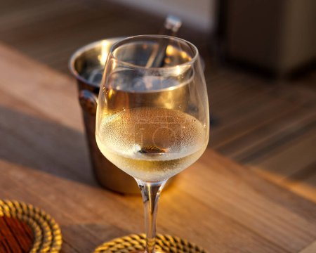 Foto de Copa de vino blanco bebidas frías en yate vela puesta del sol servido en madera de teca mesa natural - Imagen libre de derechos