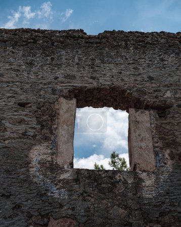 Foto de Ventana abierta en ruinas casa de piedra abandonada, vista del cielo azul - Imagen libre de derechos