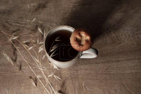 Photo for Cup of tea and cookie in brown sandy colors,natural wood rustic background, organic decoration of dry plant, mu lifestyle concept - Royalty Free Image