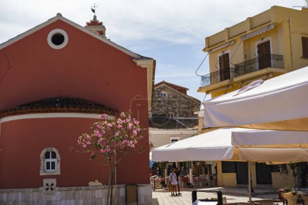 Téléchargez les photos : Port de Gaios sur l'île grecque de Paxos, 31 mai 2024 : vue sur la promenade du village en première ligne de la couchette avec bateaux, boutiques, tavernes, église - en image libre de droit