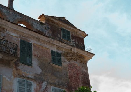 abandoned old house property with historical exterior, balcony, wooden dpprs and windows, shutters