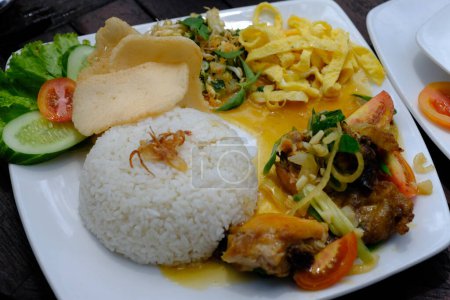 Foto de Nasi Campur, nasi rames, Nasi Campur is a dish consisting of vegetable urap, fried chicken, prawn crackers, chili sauce, and stir-fried vegetables. Indonesian food. - Imagen libre de derechos