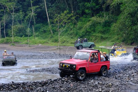 Foto de Yogyakarta, Indonesia - 19 de junio de 2022: Los jeep cars todoterreno circulan por el río. Aventura de coches todoterreno 4x4 en terreno natural en Indonesia. - Imagen libre de derechos