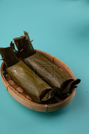 Foto de Lontong es un plato indonesio hecho de pastel de arroz comprimido en forma de cilindro envuelto en el interior. Lontong en la cesta de bambú tejida. - Imagen libre de derechos