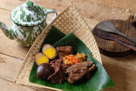 Photo for Gudeg krecek is a traditional Yogyakarta food made from young jackfruit, egg, chicken, coconut milk, brown sugar, and spices. served in woven bamboo and banana leaf containers. Indonesian food. - Royalty Free Image