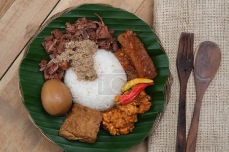 Photo for Nasi Gudeg Krecek is rice and gudeg, which is made from processed young jackfruit, coconut milk, spices, tofu, eggs and chicken. Yogyakarta specialties. Indonesian food. Served with banana leaves. - Royalty Free Image