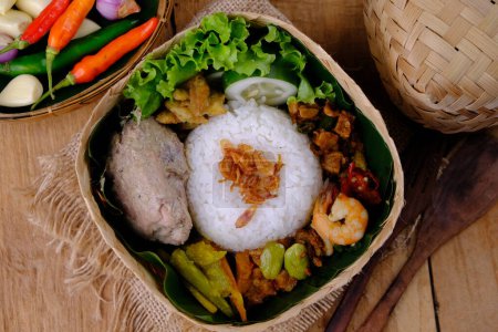 Téléchargez les photos : Nasi Berkat Pekalongan. est du riz avec des plats d'accompagnement de poulet frit, légumes épicés sautés, légumes frais. nasi kenduri. ayam santan, sambal goreng, tumis sayur, acar kuning. Alimentation indonésienne - en image libre de droit