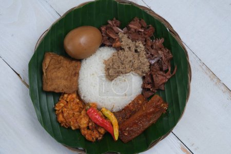 Photo for Nasi Gudeg Krecek is rice and gudeg, which is made from processed young jackfruit, coconut milk, spices, tofu, eggs and chicken. Yogyakarta specialties. Indonesian food. Served with banana leaves. - Royalty Free Image