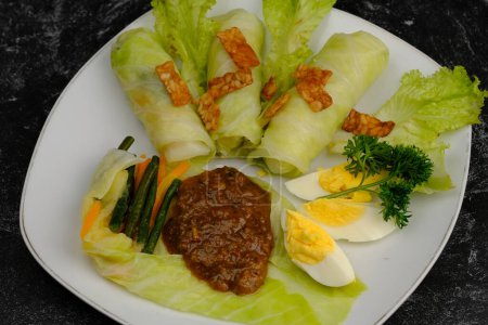 Photo for Pecel is a food that is combined with peanut sauce seasoning as the main ingredient and mixed with various types of boiled vegetables and fresh vegetables, and boiled eggs. sprinkling of fried tempeh - Royalty Free Image
