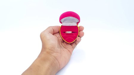 Foto de Male hands holding open pink heart shaped ring box with wedding rings inside isolated on white background - Imagen libre de derechos