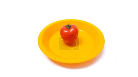 Foto de Tomato on a yellow plate isolated on white background - Imagen libre de derechos