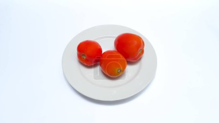 Foto de Close up of tomatoes on a plate isolated on white background - Imagen libre de derechos