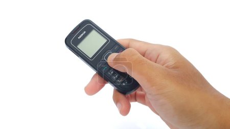 Foto de Hand holding Nokia cellphone isolated on white background. Nokia 1202 series. The old type. Jakarta, Indonesia - January 19, 2023. - Imagen libre de derechos