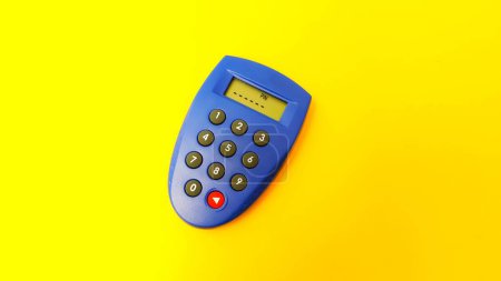 Téléchargez les photos : Blue internet banking token used to generate passwords for online transactions isolated on yellow background. Enter PIN number. - en image libre de droit