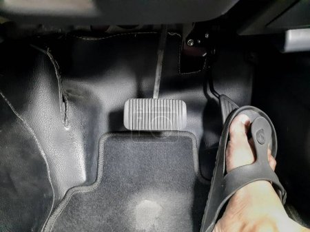 Téléchargez les photos : Close up images of man driving car by pushing accelerator and brake pedal with right foot with slippers - en image libre de droit