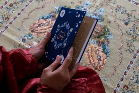 Nahaufnahme einer muslimischen Frau, die den Koran oder das Yasin-Buch in der Hand hält