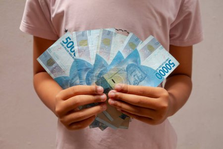 Asian child holding Indonesian money. Fifty thousand rupiah. Indonesian rupiah banknotes.