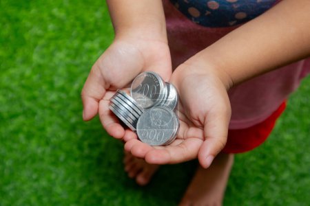 Monedas indonesias en manos. Niño asiático sosteniendo moneda indonesia dinero. Ahorro de dinero y concepto de inversión.
