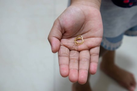 A child holding gold earrings in the palm of her hand