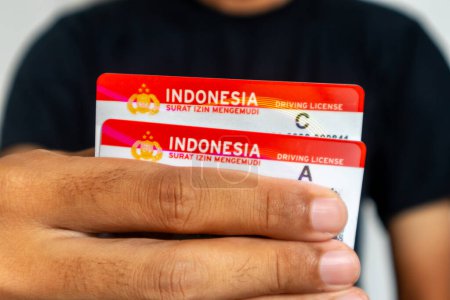 Photo for Jakarta, Indonesia - March 13, 2024: A man in black clothes holding the Indonesia driving license for car and motorcycle - Royalty Free Image