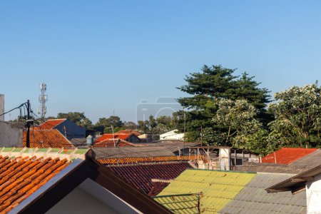 Vista de tejados de tejas y árboles con cielo azul claro en una zona residencial en el suburbio de Yakarta
