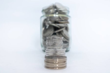 Indonesian Rupiah coins in glass jar and stacked coins with white background