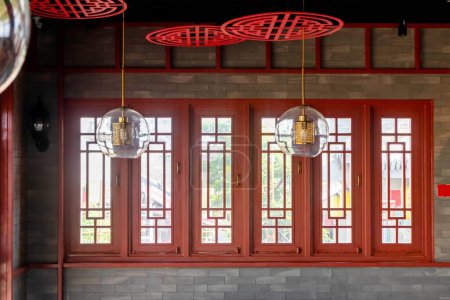 Red wooden window in brick wall with traditional Chinese style with hanging lamp. Interior view.