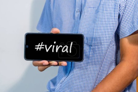 Man holding a smartphone with hashtag viral on screen. Viral content on social media concept.