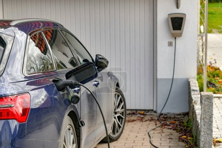 Photo for An electric car is charged from a gas station in a private house. - Royalty Free Image