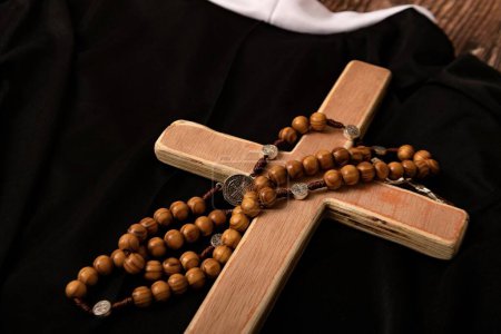 Téléchargez les photos : Croix catholique, chapelet avec des perles reposent sur les vêtements noirs du prêtre. - en image libre de droit