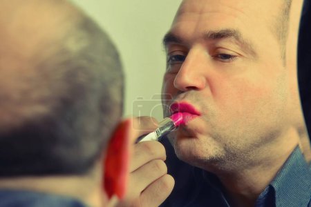 Téléchargez les photos : Homme adulte peint les lèvres avec du rouge à lèvres rouge, la mode et le style d'un homme avec des vues indépendantes, image tonique gros plan
. - en image libre de droit