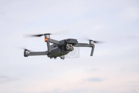 Un drone volant contre un ciel nuageux par temps nuageux prend des photos de la surface de la terre.