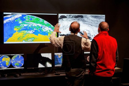 Téléchargez les photos : Deux hommes discutent des problèmes météorologiques au poste de contrôle de la mission. Photo de haute qualité - en image libre de droit