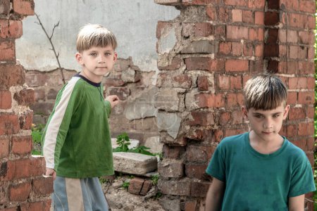 Kinder in einem verlassenen Haus, zwei arme verlassene Jungen, Waisen infolge von Naturkatastrophen und Militäraktionen. Einreichungsfoto.