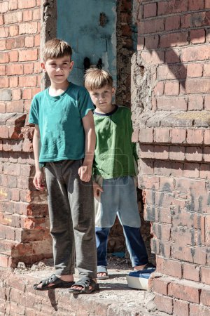 Téléchargez les photos : Deux petits frères sont orphelins, vivant dans une maison abandonnée et abandonnée, enfants de la guerre. Photo mise en scène
. - en image libre de droit