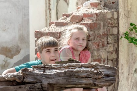 Children in an abandoned and destroyed building in the zone of military and military conflicts. The concept of social problems of homeless children. Staged photo.