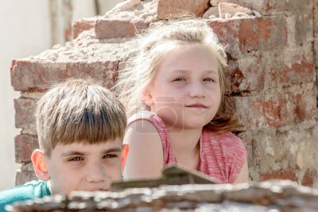 Enfants dans un bâtiment abandonné et détruit dans la zone de conflits militaires et militaires. Le concept des problèmes sociaux des enfants sans abri. Photo mise en scène
.