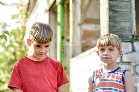 Two brothers are standing near a burned-out house, who lost their homes as a result of hostilities and natural disasters.