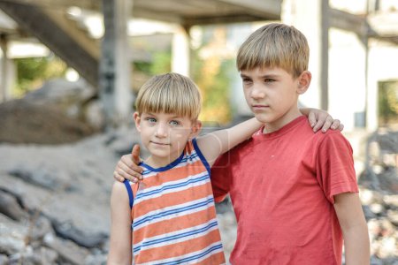 zwei Brüder stehen in einer Umarmung vor dem Hintergrund eines unvollendeten und verlassenen Gebäudes, ein Konzept für das Leben von Straßenkindern von Waisenkindern.