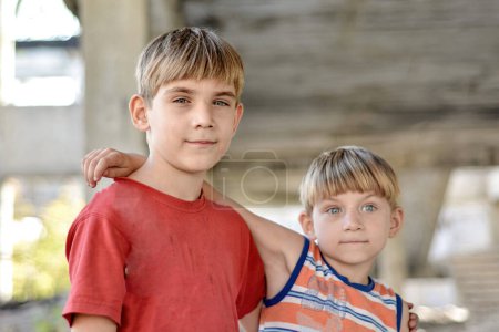 Two brothers are standing in an embrace against the backdrop of an unfinished and abandoned building, a concept of the life of street children of orphans.