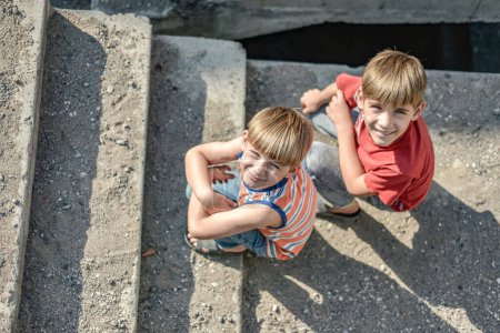 zwei Kinder sitzen auf den Stufen eines verlassenen Gebäudes, ein Konzept für das Leben von Straßenkindern Waisenkindern.