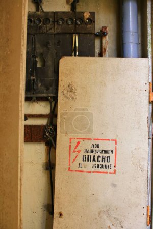 Téléchargez les photos : Mots russes sur une boîte à fusibles cassée : Tension - danger pour la vie!. - en image libre de droit