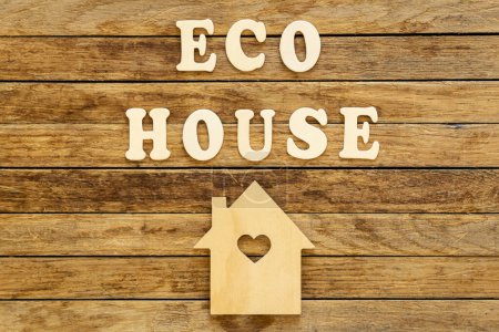 Foto de Inscripción Eco casa hecha de letras de madera y modelo de casa sobre un fondo de madera, disposición plana. - Imagen libre de derechos