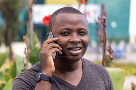 Photo for A young african man receives good news from a phone call running in a city garden - Royalty Free Image