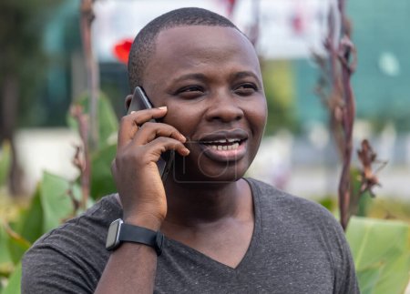 Photo for A young african man receives good news from a phone call running in a city garden - Royalty Free Image
